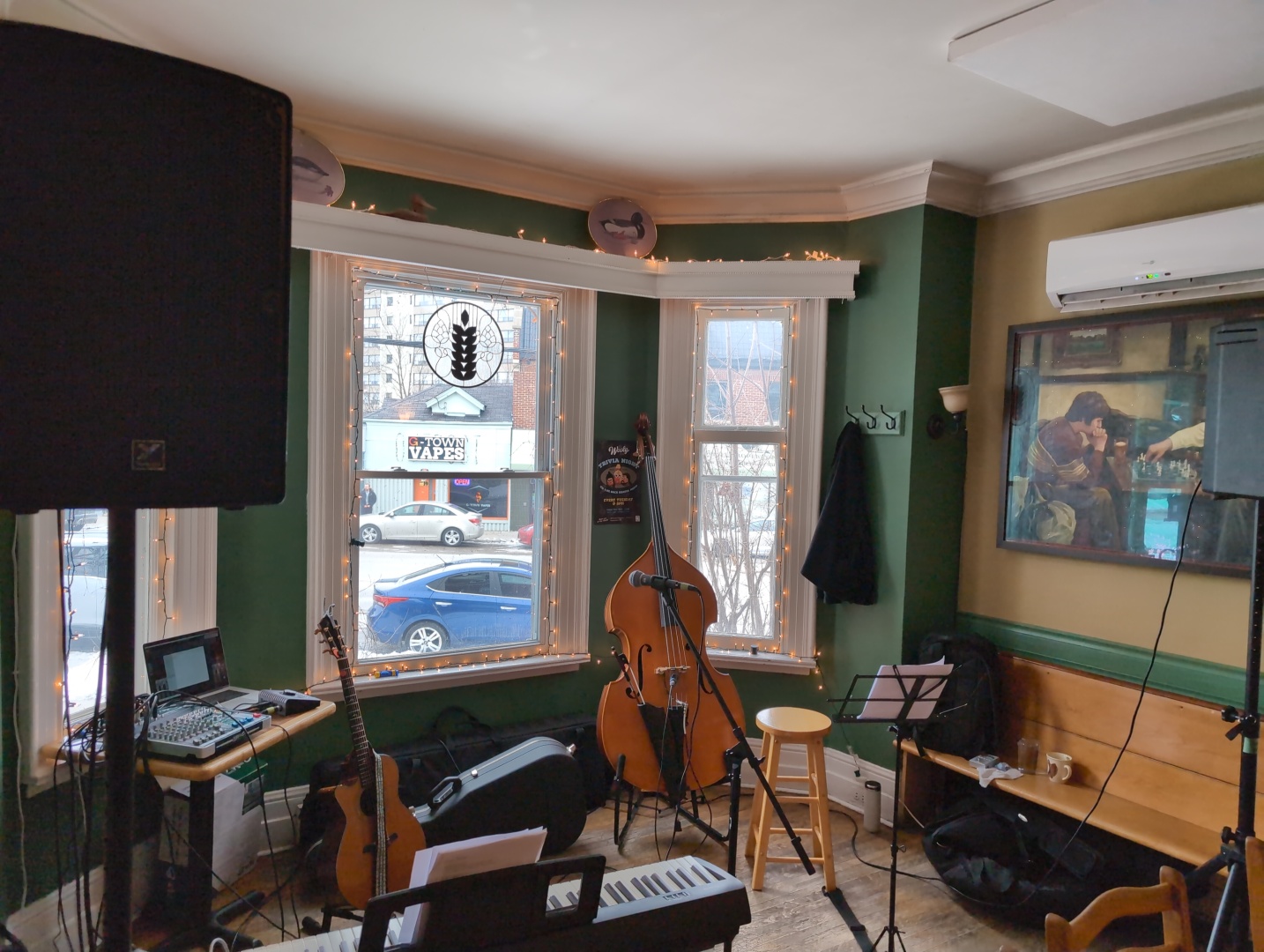 The salon of an old house that was turned into a pub. It's set up for a live music performance with an acoustic guitar, double bass, keyboard, and PA system.