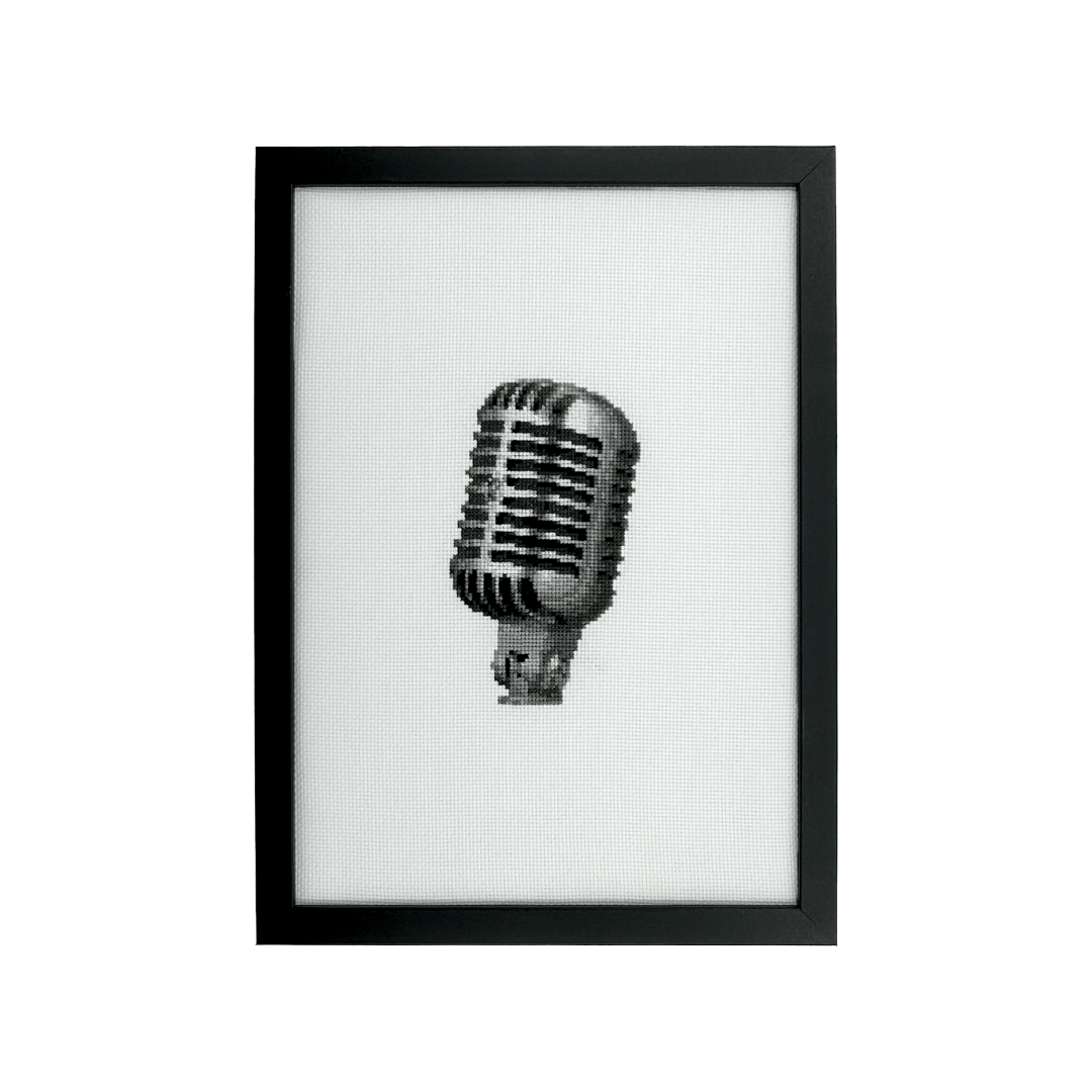cross stitch of a shure 55 SH mic in an impressionistic style on white fabric in a black frame