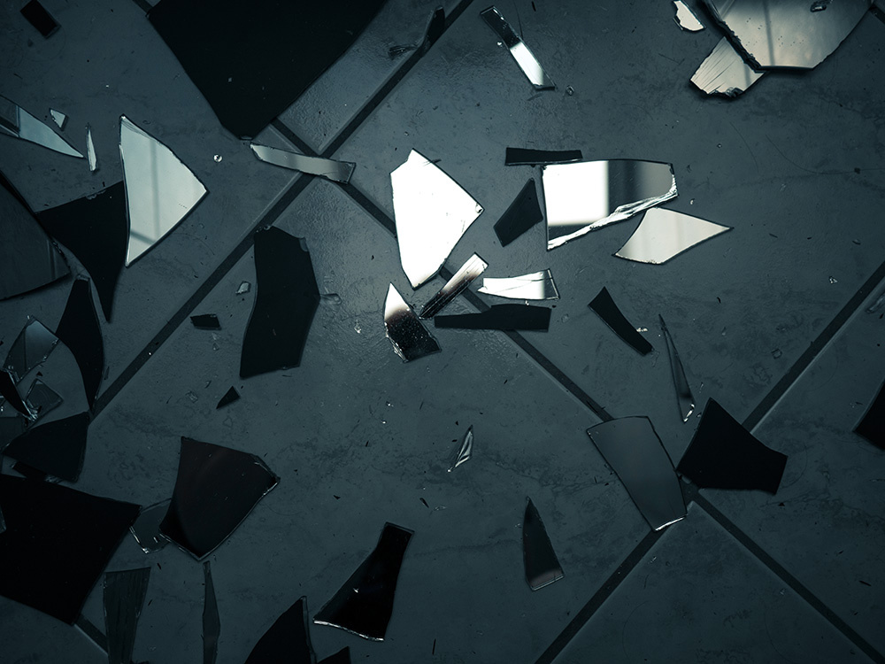 Shards of a mirror on the tiles of a bathroom floor.