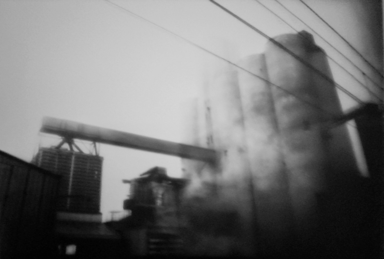 photo prise depuis un train, on voit une usine derrière la brume.