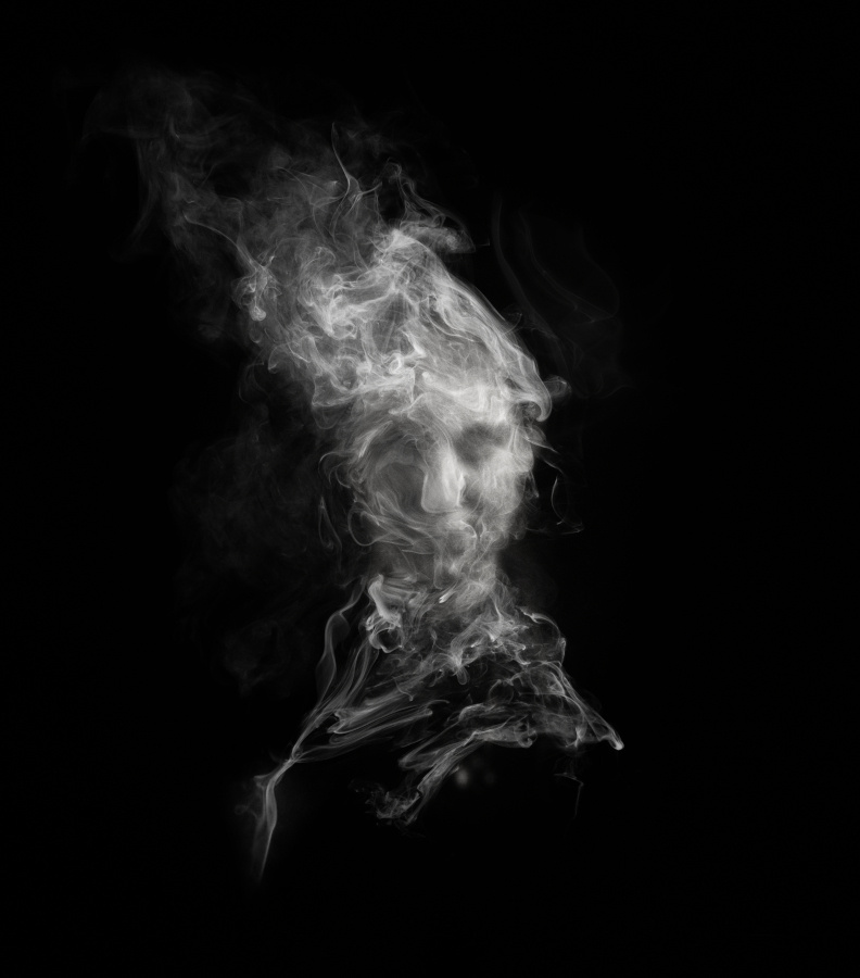 A black and white image based on a portrait pinhole photograph, layered with textures and digitally created smoke