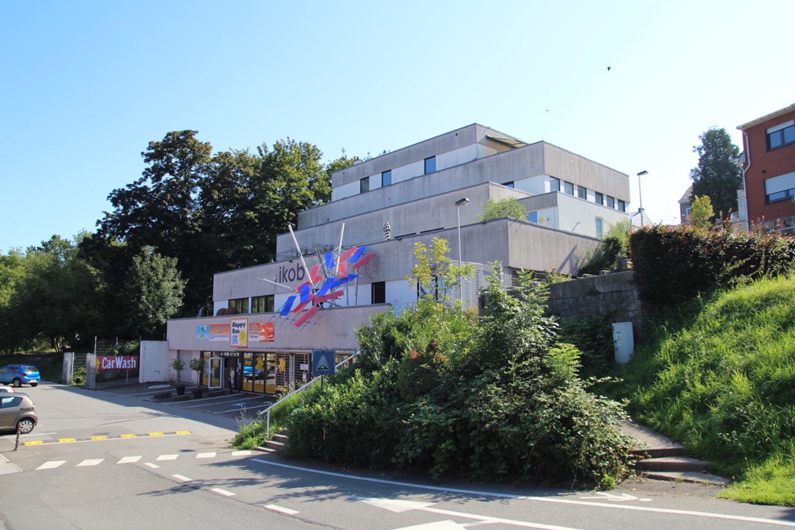 You see a multi storage building, that is home to a solarium, IKOB - Museum or Contemporary art, as well as private apartments. "Lichtschlag" an Artwork by Paul Schwer is a kind of signature work that greets the visitors from the 1 floor terrace.